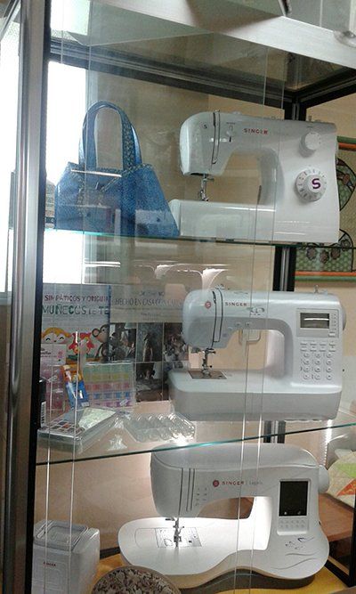 Una vitrina llena de máquinas de coser y bolsos.