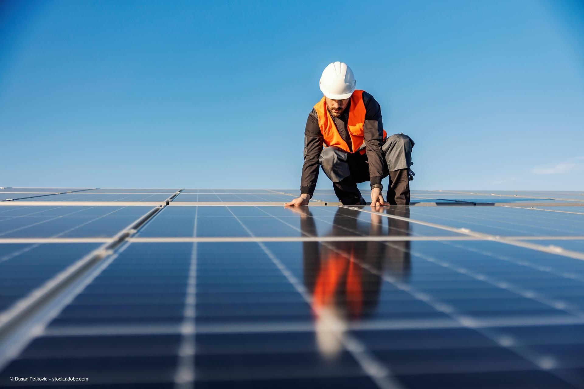 Eine Person installiert Photovoltaikanlagen