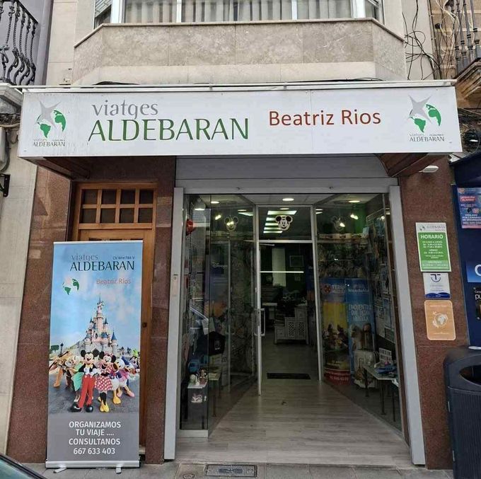 Fachada de una agencia de viajes con un letrero verde y blanco que dice “Viatges Aldebaran” y “Beatriz Rios”.