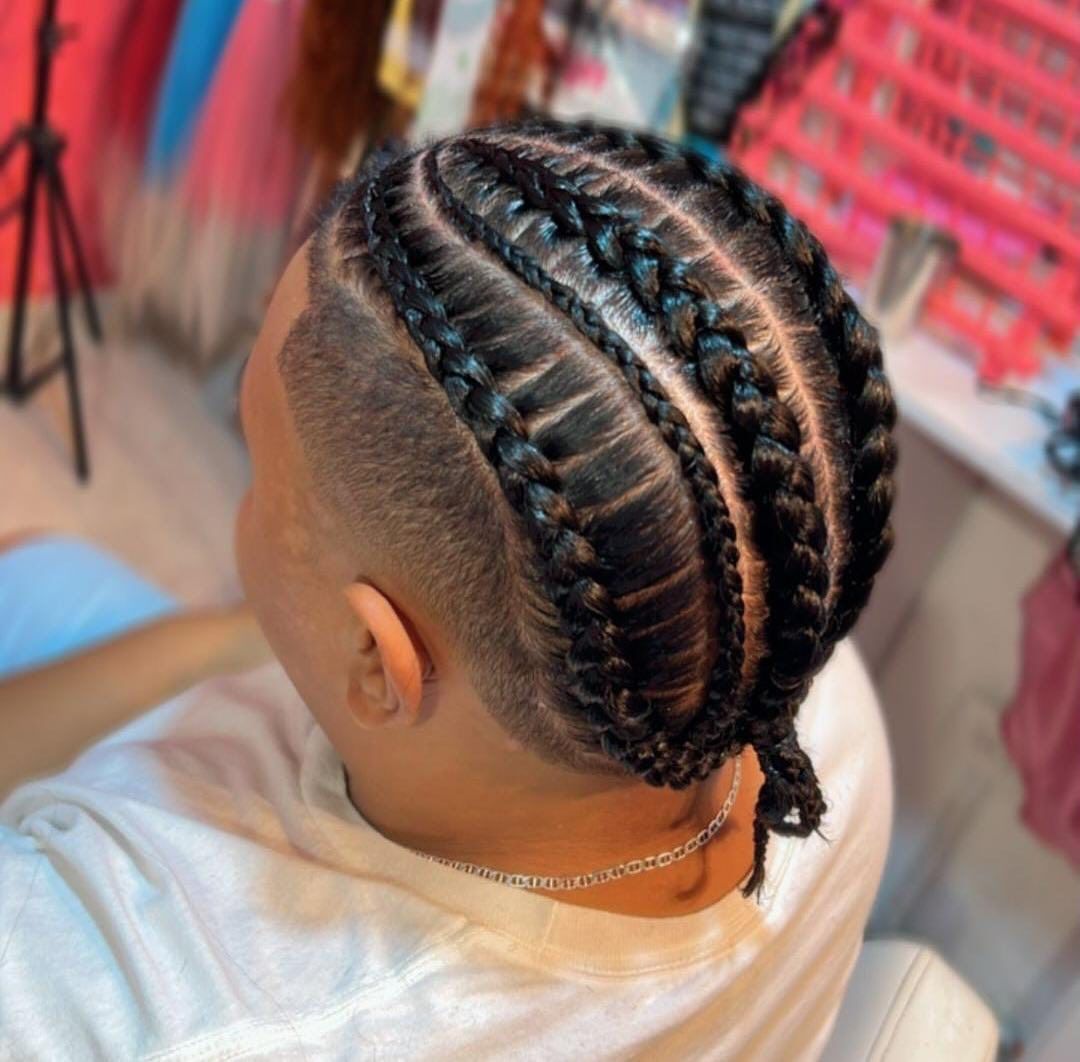 Un hombre con trenzas en el pelo está sentado en una silla.