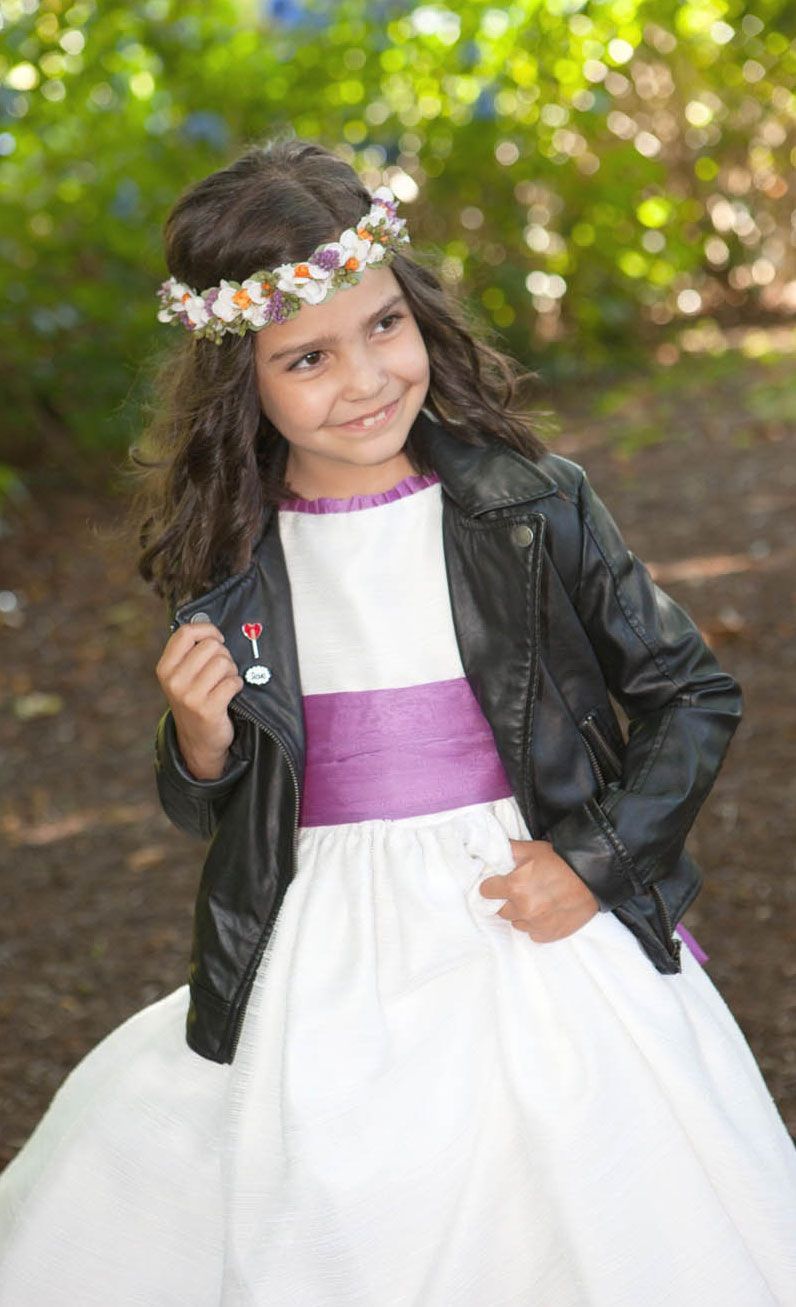 Una niña que lleva un vestido blanco y una chaqueta de cuero negra.