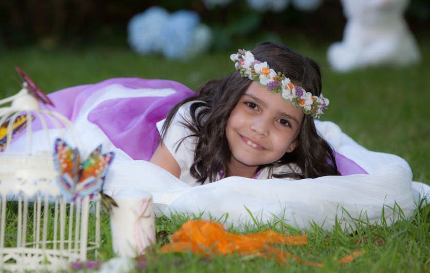 Una niña que lleva una corona de flores está tumbada en el césped.