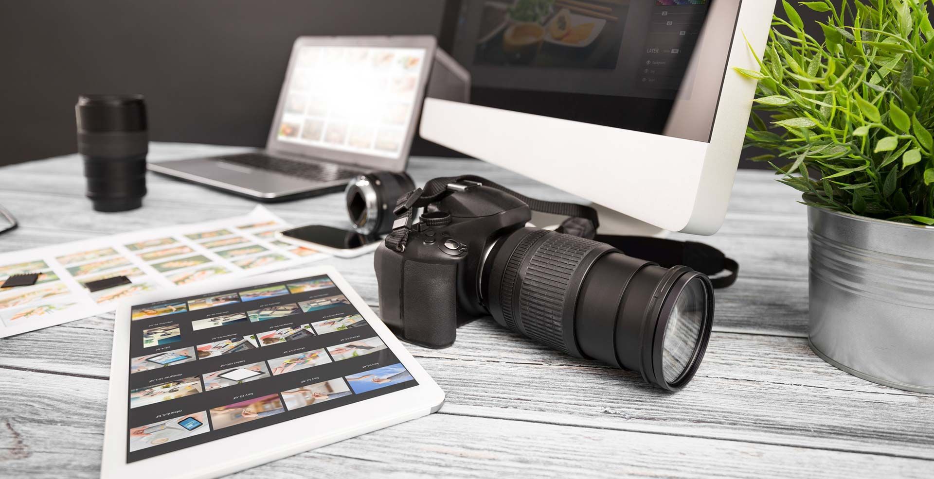Una cámara está sobre una mesa al lado de una tableta y una computadora.