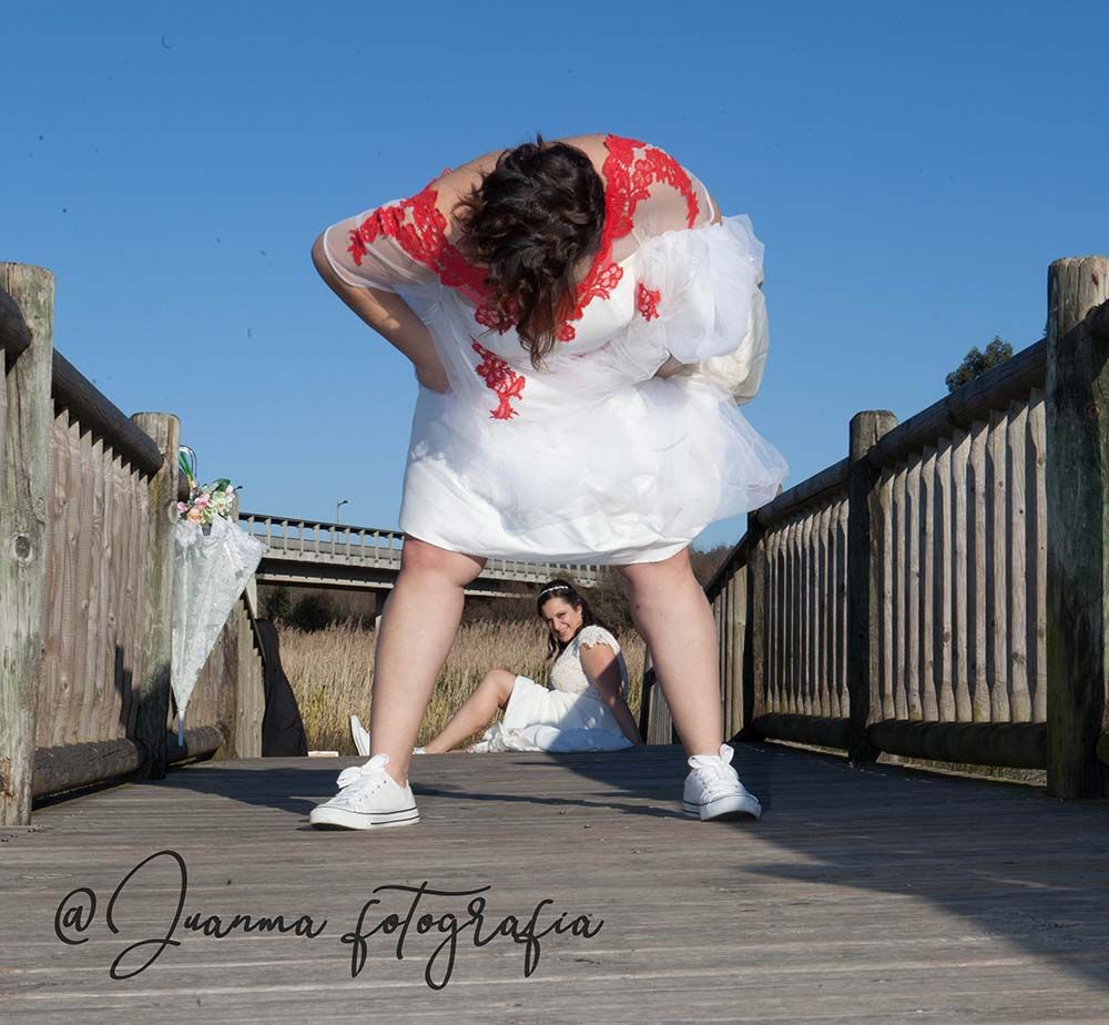 Una mujer con un vestido blanco está inclinada sobre un puente de madera.