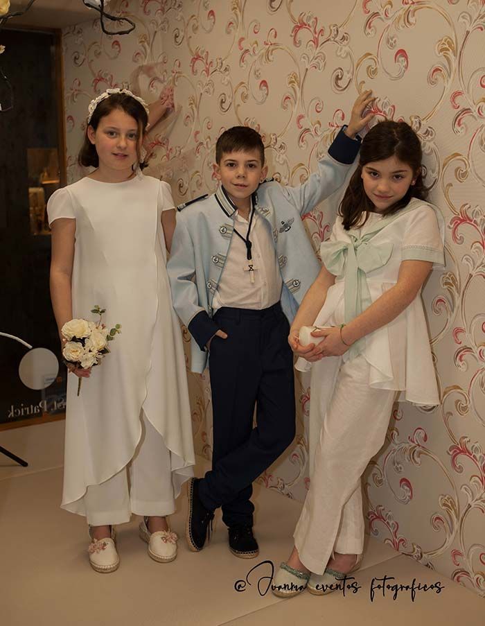 Un niño y dos niñas posan para una foto frente a una pared.