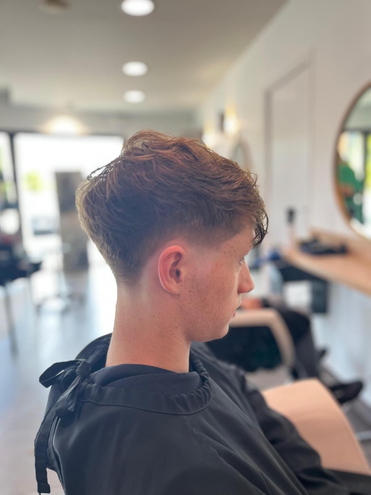 Jeune personne avec une coupe de cheveux délavée dans un salon de coiffure.