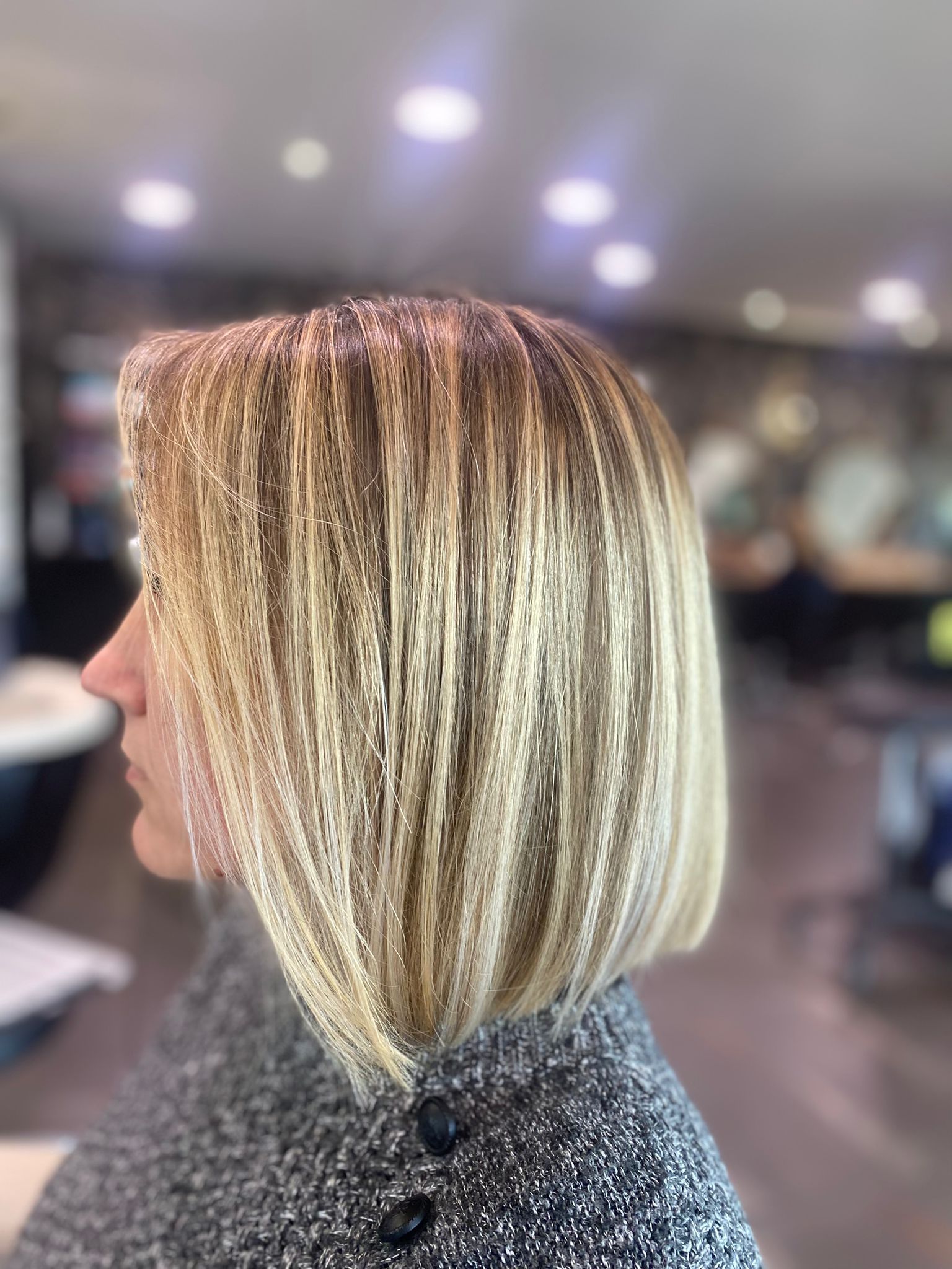 Femme avec une coupe au carré dégradée, blonde et brune, dans un salon de coiffure.