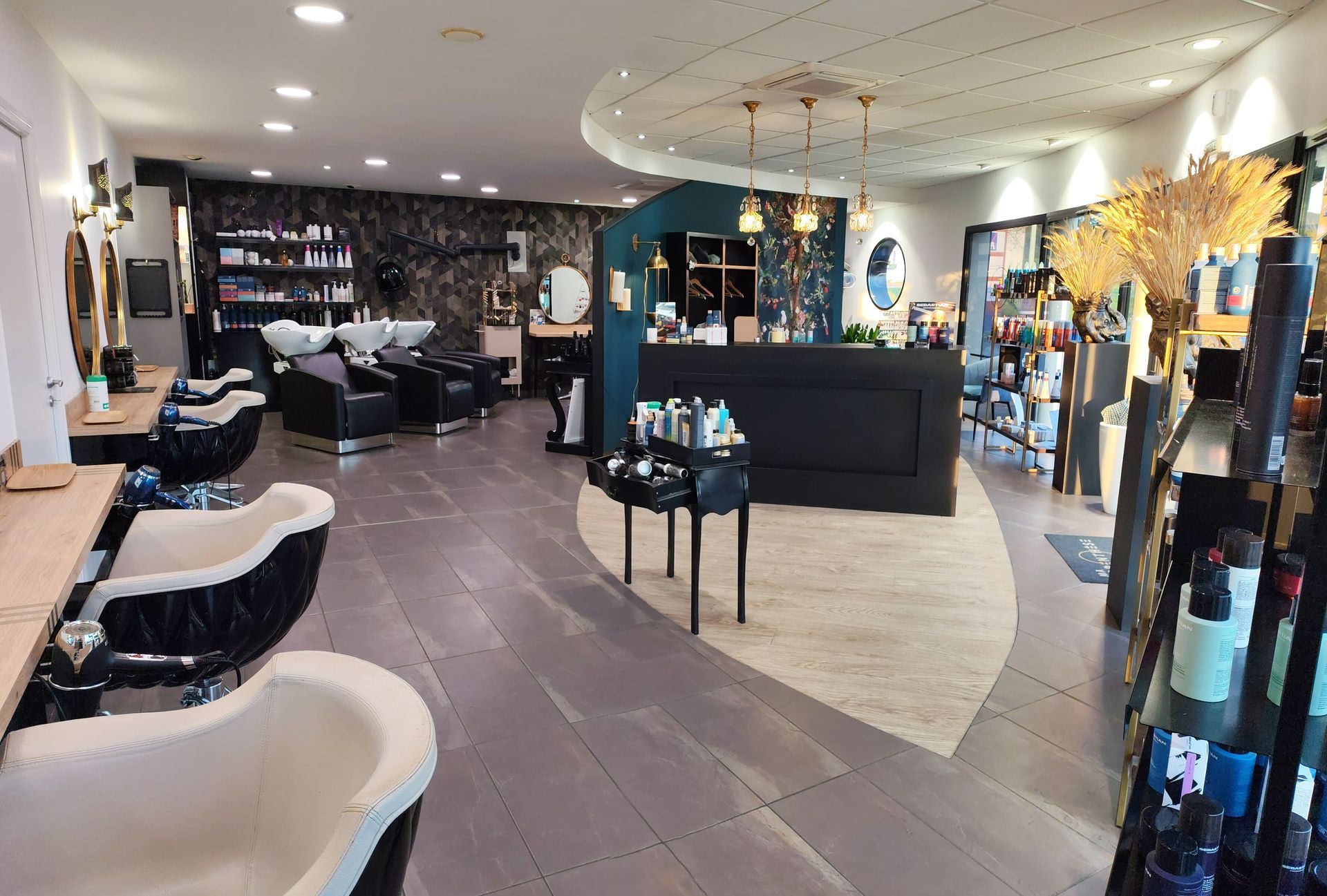 Intérieur d'un salon de coiffure moderne avec postes de travail, présentoirs de produits et comptoir d'accueil.