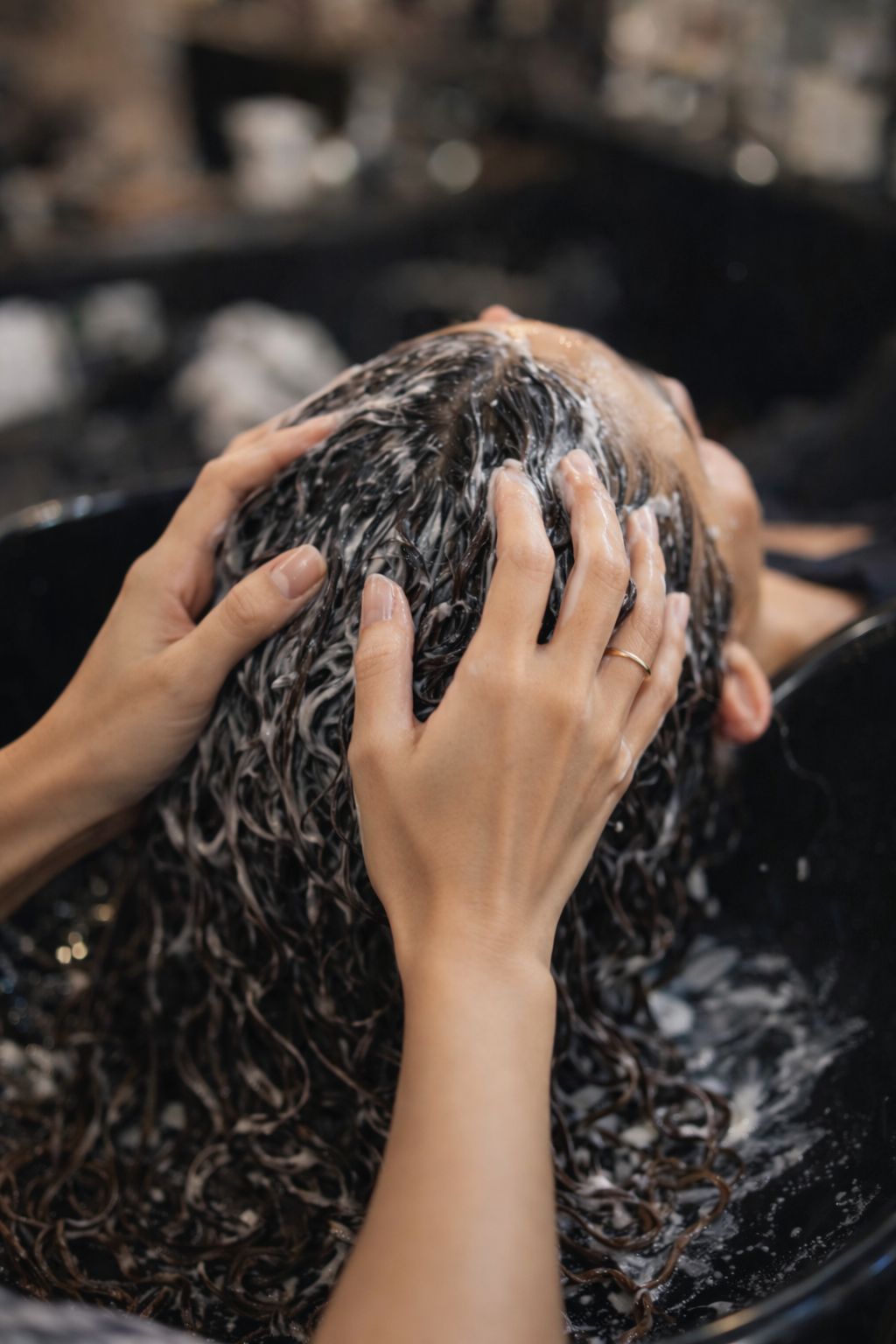 Se laver les cheveux à la main avec du shampoing dans un lavabo de salon.