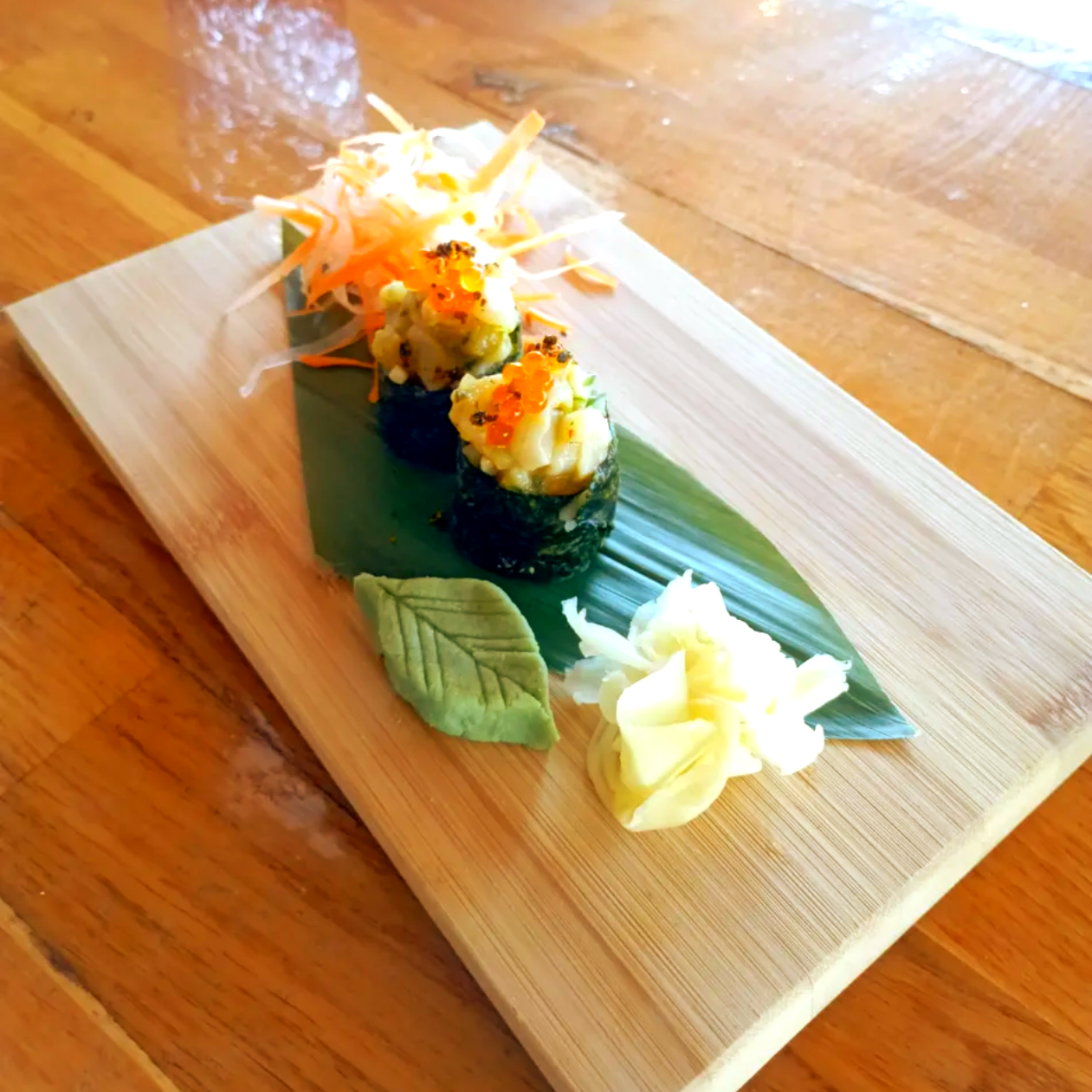 Surtido de rollos de sushi con guarnición en una tabla de madera.