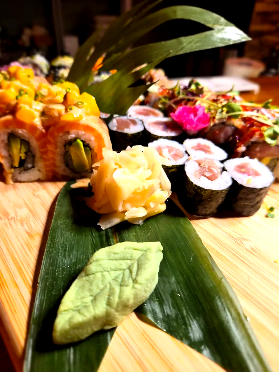 Surtido de rollos de sushi y nigiri dispuestos sobre una hoja de plátano en una mesa de madera.