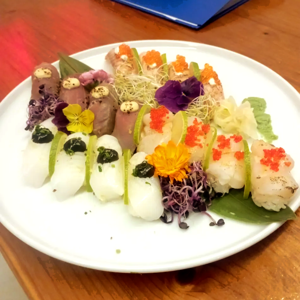 Plato variado de sushi con coloridos adornos en un plato blanco.