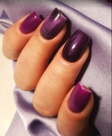 Un primer plano de las uñas de una mujer con esmalte de uñas morado.