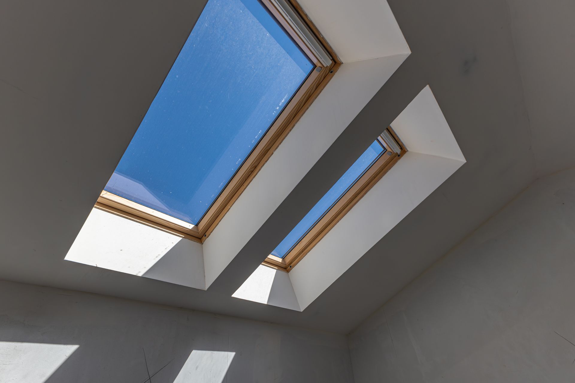Deux puits de lumière intégrés à un plafond blanc laissent entrevoir le ciel bleu et la lumière du jour.