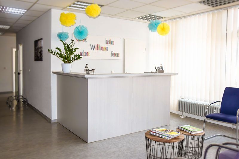 Ein Wartezimmer mit einem weißen Tresen und einem blauen Stuhl