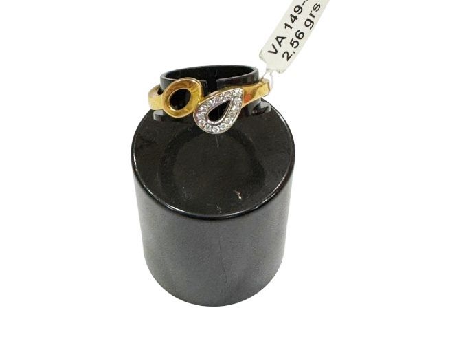 Anillo de oro con detalles en negro y diamantes sobre soporte de exhibición negro.