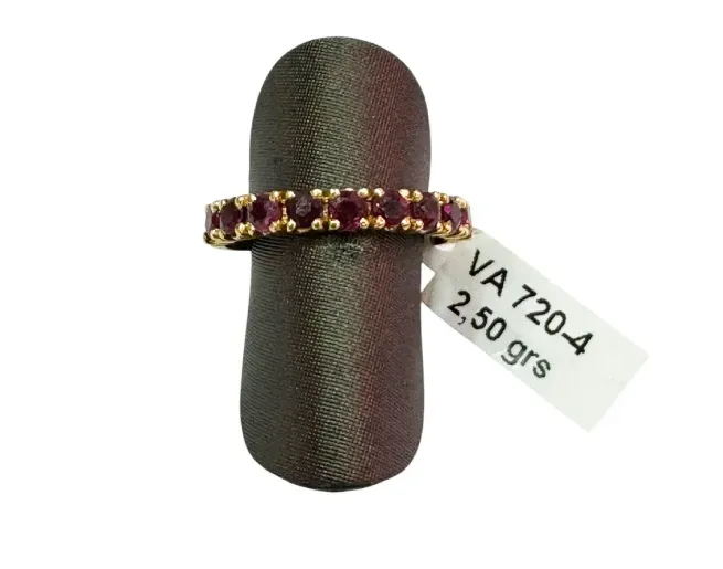 Anillo de oro con piedras rojas sobre expositor de color marrón oscuro, con etiqueta de precio que indica 2,50 gramos.