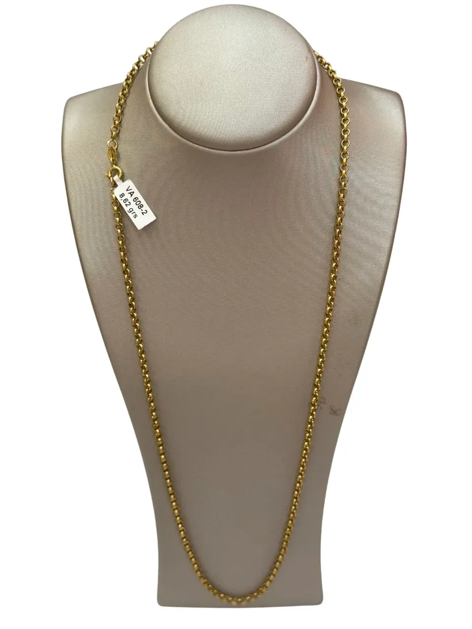 Collar de cadena de oro exhibido en un maniquí beige.