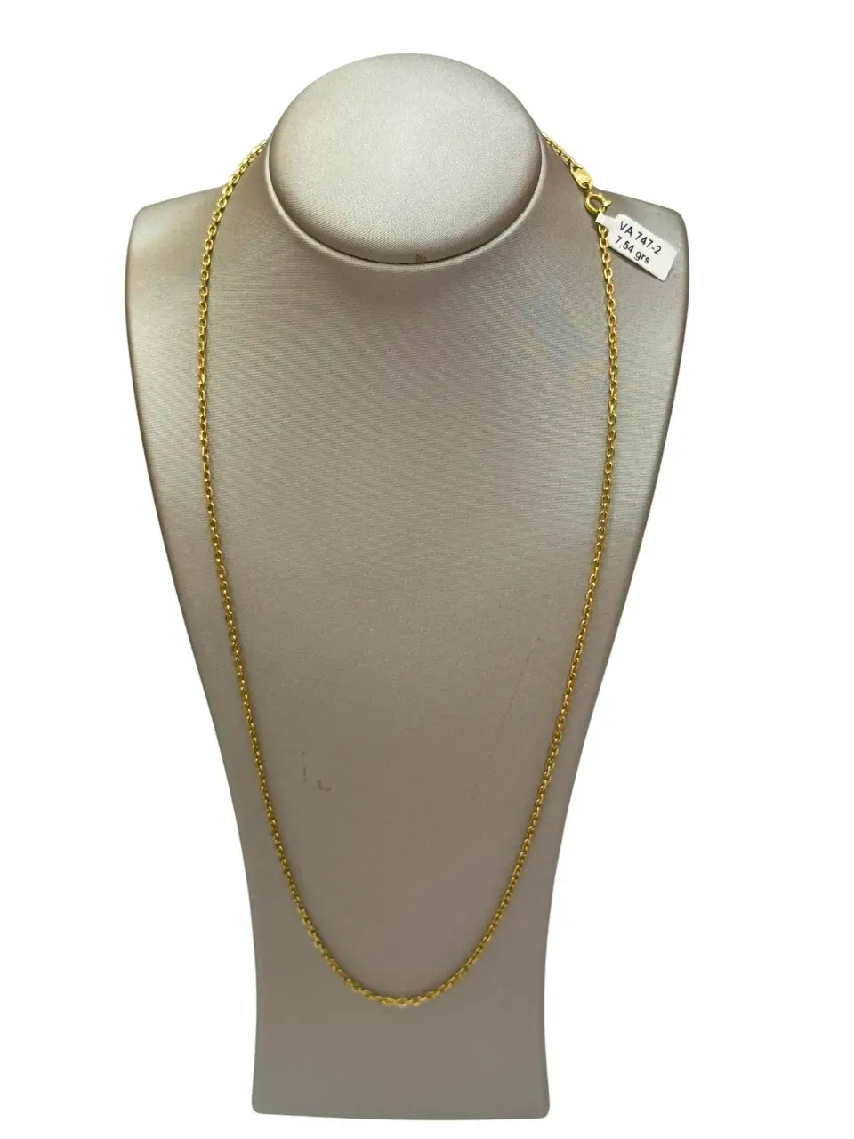 Collar de oro colocado sobre un maniquí de color crema, fondo blanco.