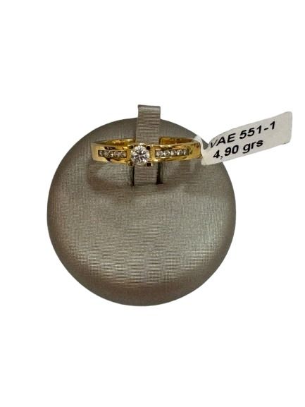 Anillo de oro con un pequeño diamante en expositor gris.