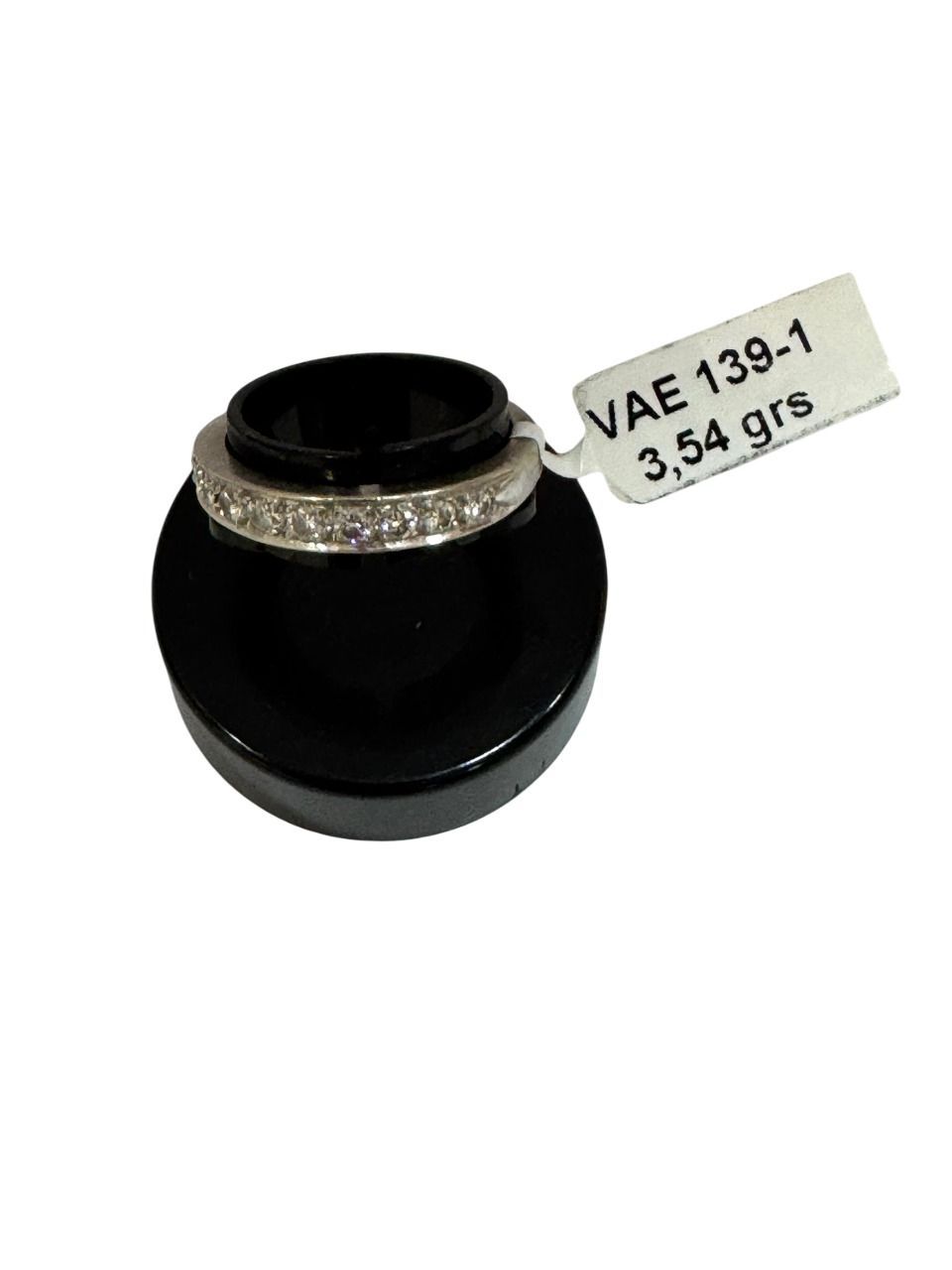 Anillo con pequeñas gemas expuestas sobre un soporte negro, una etiqueta dice