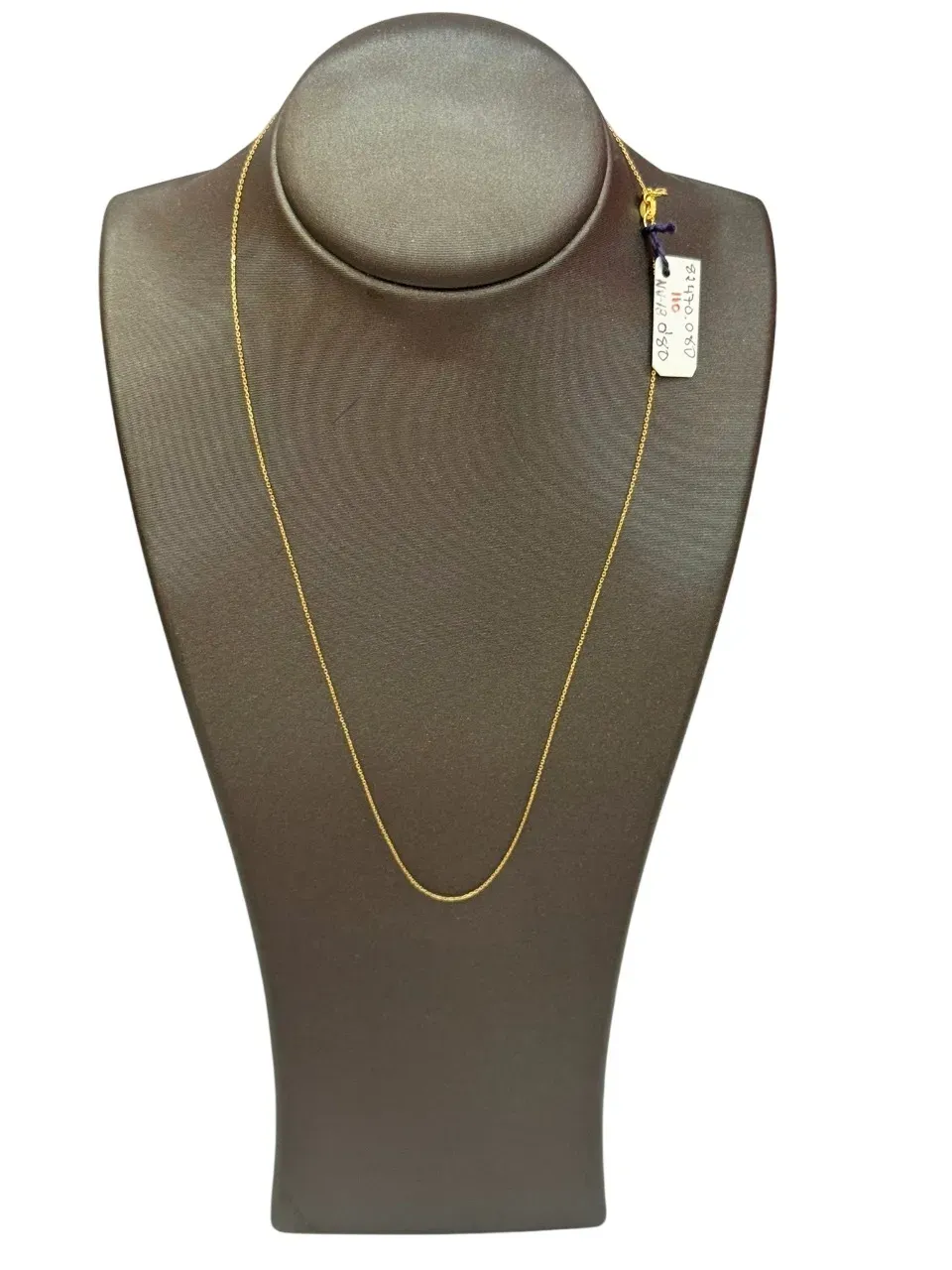 Collar de oro exhibido en un busto de joyería marrón; etiqueta visible.