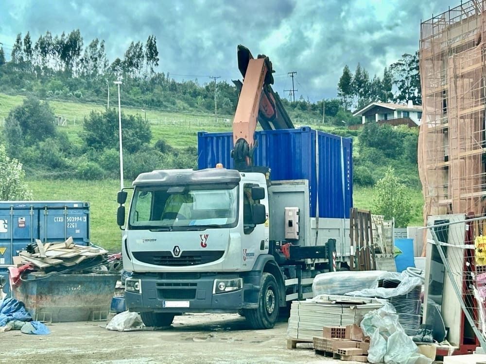 Un camión con una grúa en la parte trasera está estacionado en un sitio de construcción.