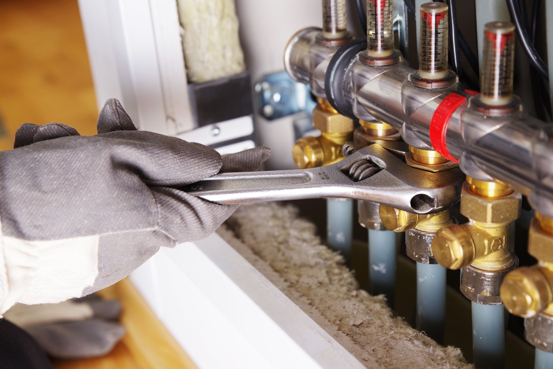 Eine Person trägt mit einer Handkelle und einem Putzbrett grauen Putz auf eine weisse Wand auf.