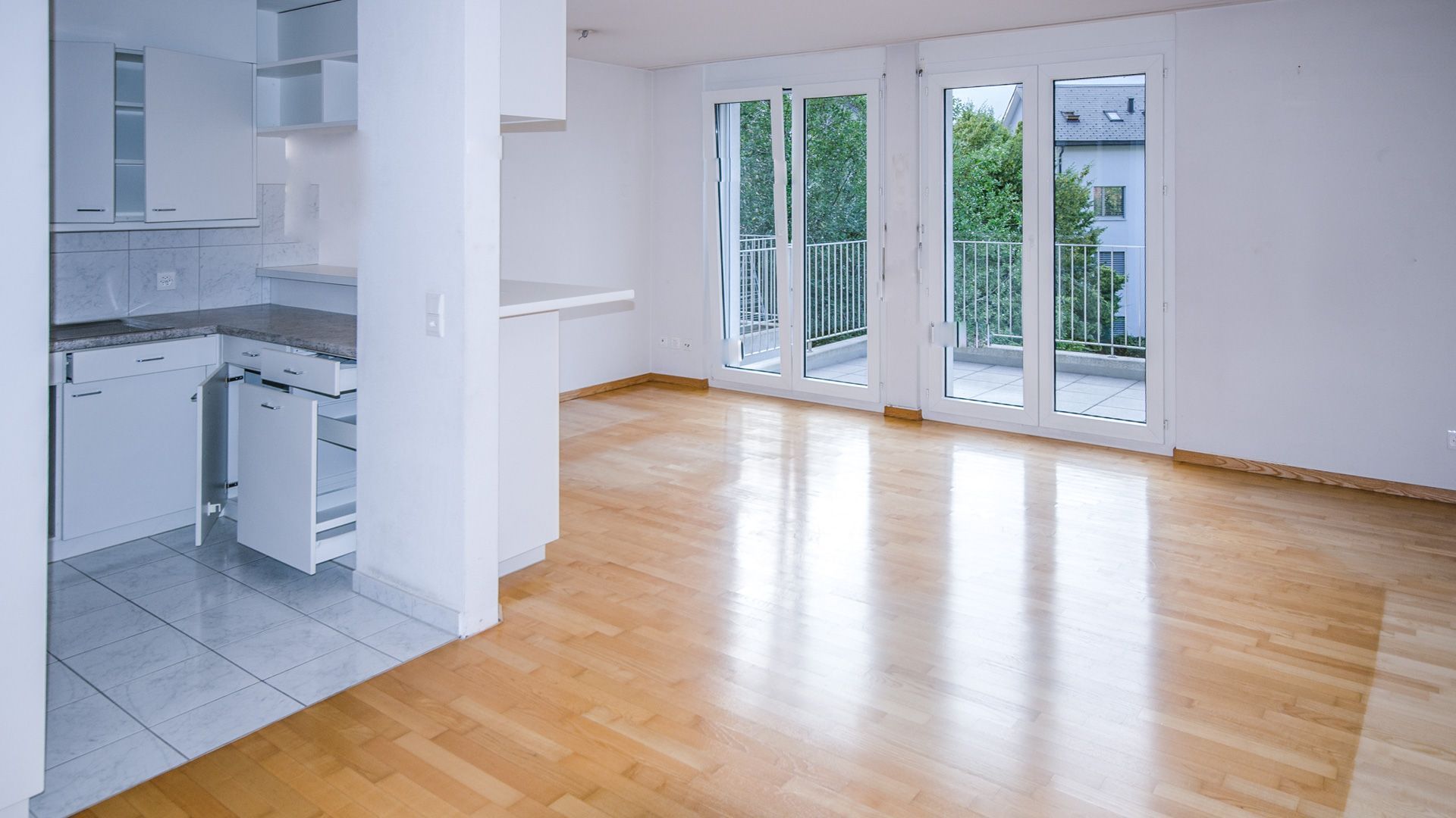 Ein eingeschossiges, cremefarbenes Stuckhaus mit Schindeldach, Bogenfenstern mit Fensterläden und einem angelegten Vorgarten.