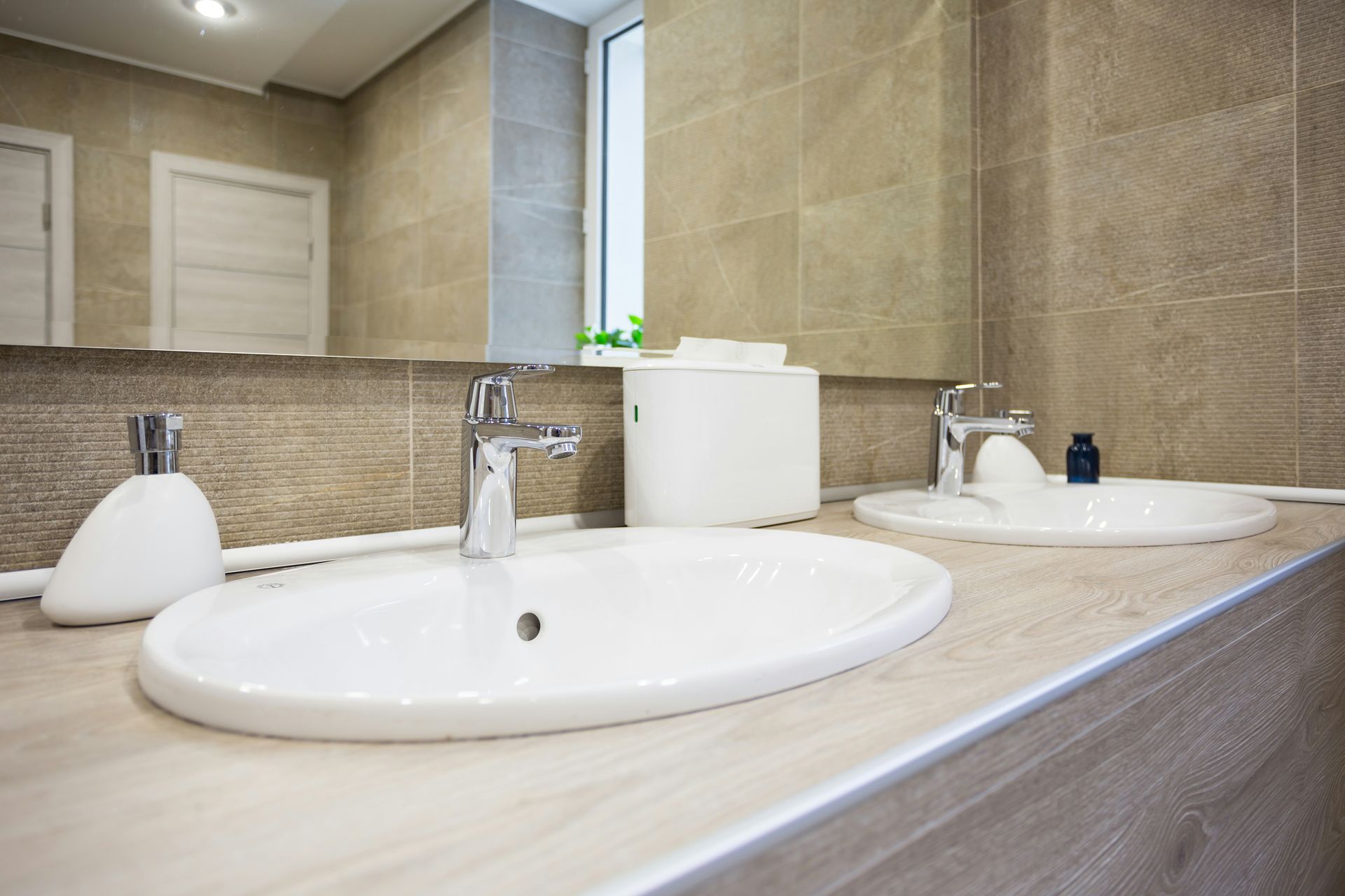 Eine weiss geflieste, leere Küche mit weissen Schränken, Spüle, Herd und offenem Kühlschrank.