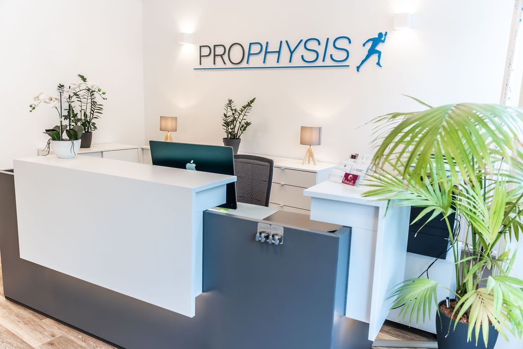 Rezeptionstresen mit „PROPHYSIS“-Logo und Zimmerpflanzen.
