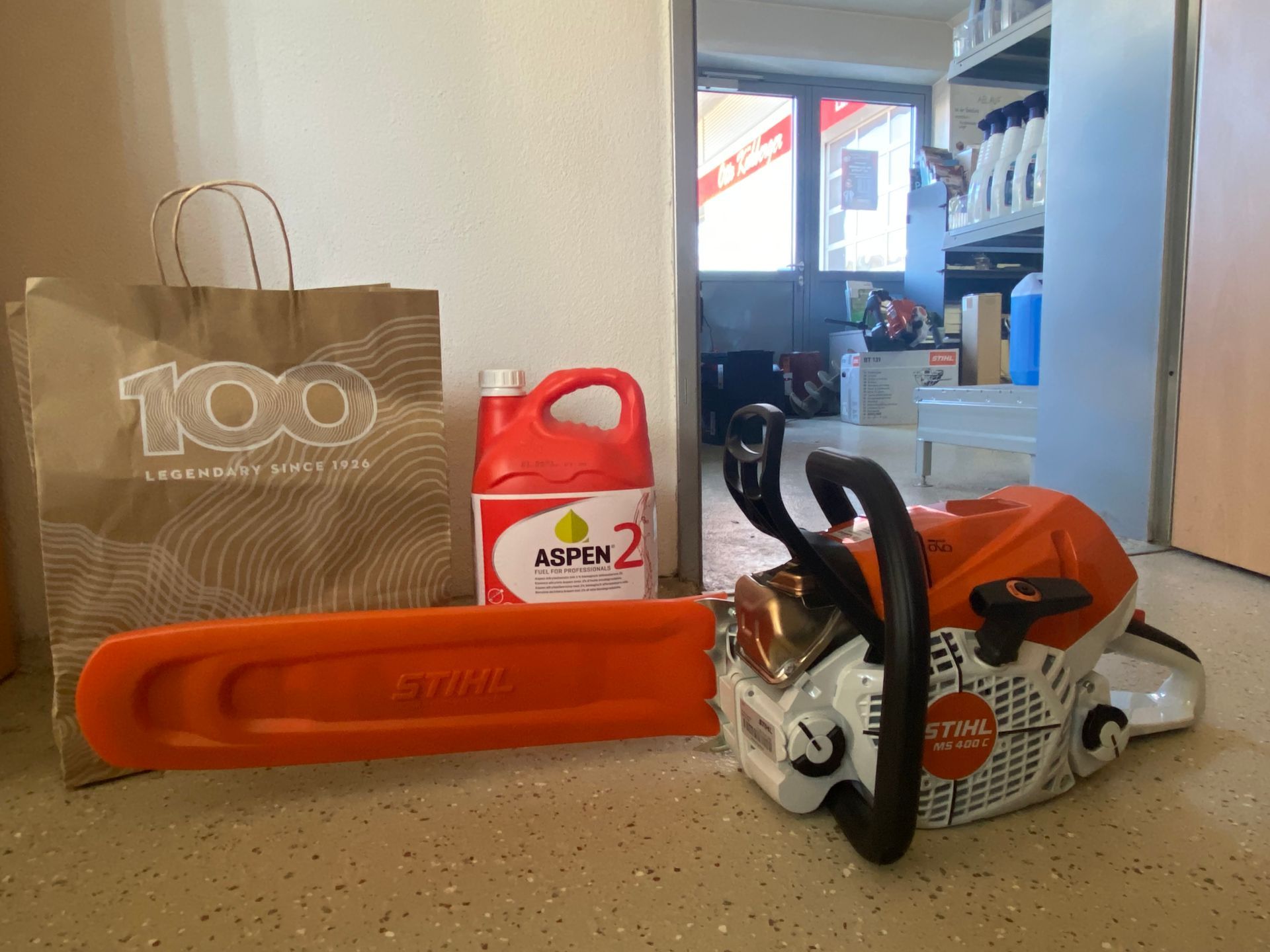 STIHL Motorsäge mit Schwertschutz, Aspen 2 Kraftstoffkanister und einer Papiertasche auf einem Tisch