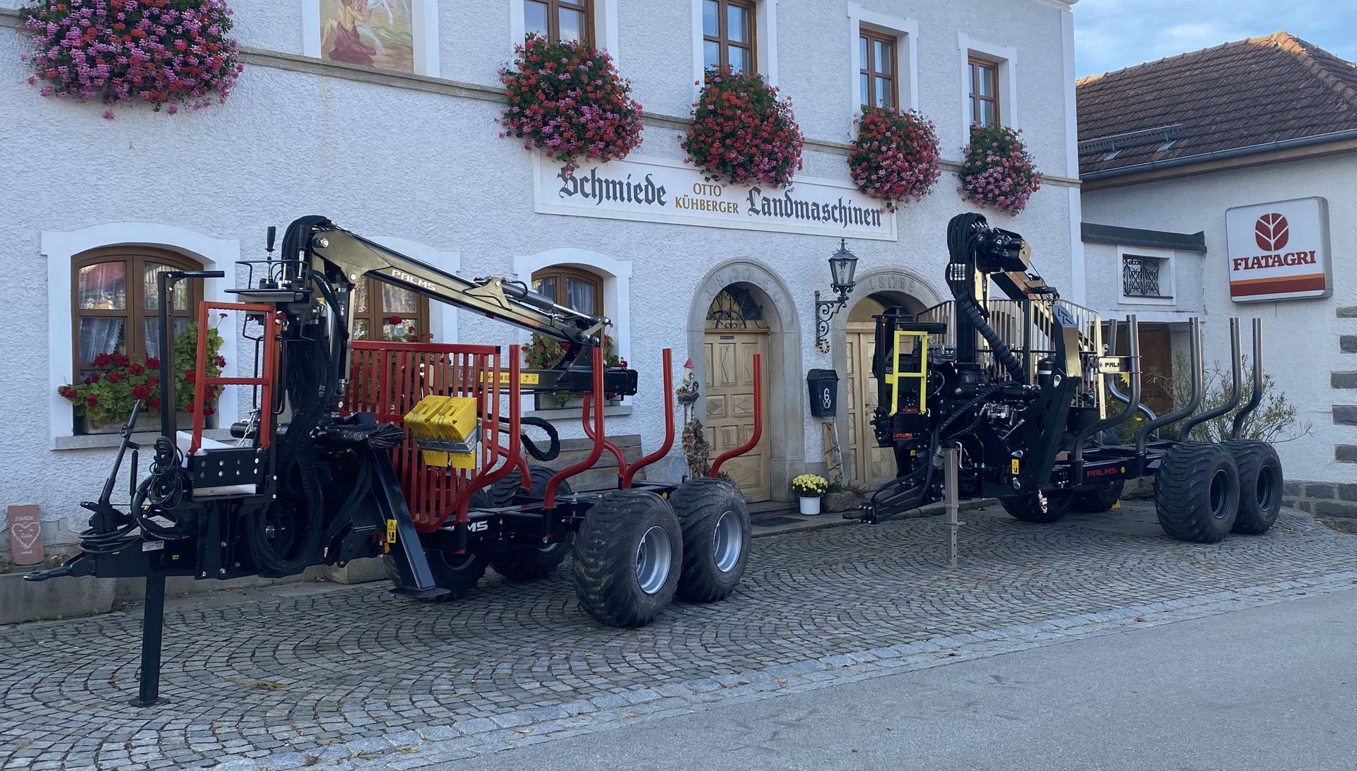 Zwei Rückewägen mit Forstkränen geparkt vor einem Betriebsgebäude
