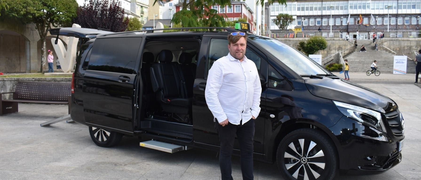 Un hombre con una camisa blanca está parado frente a una camioneta negra.