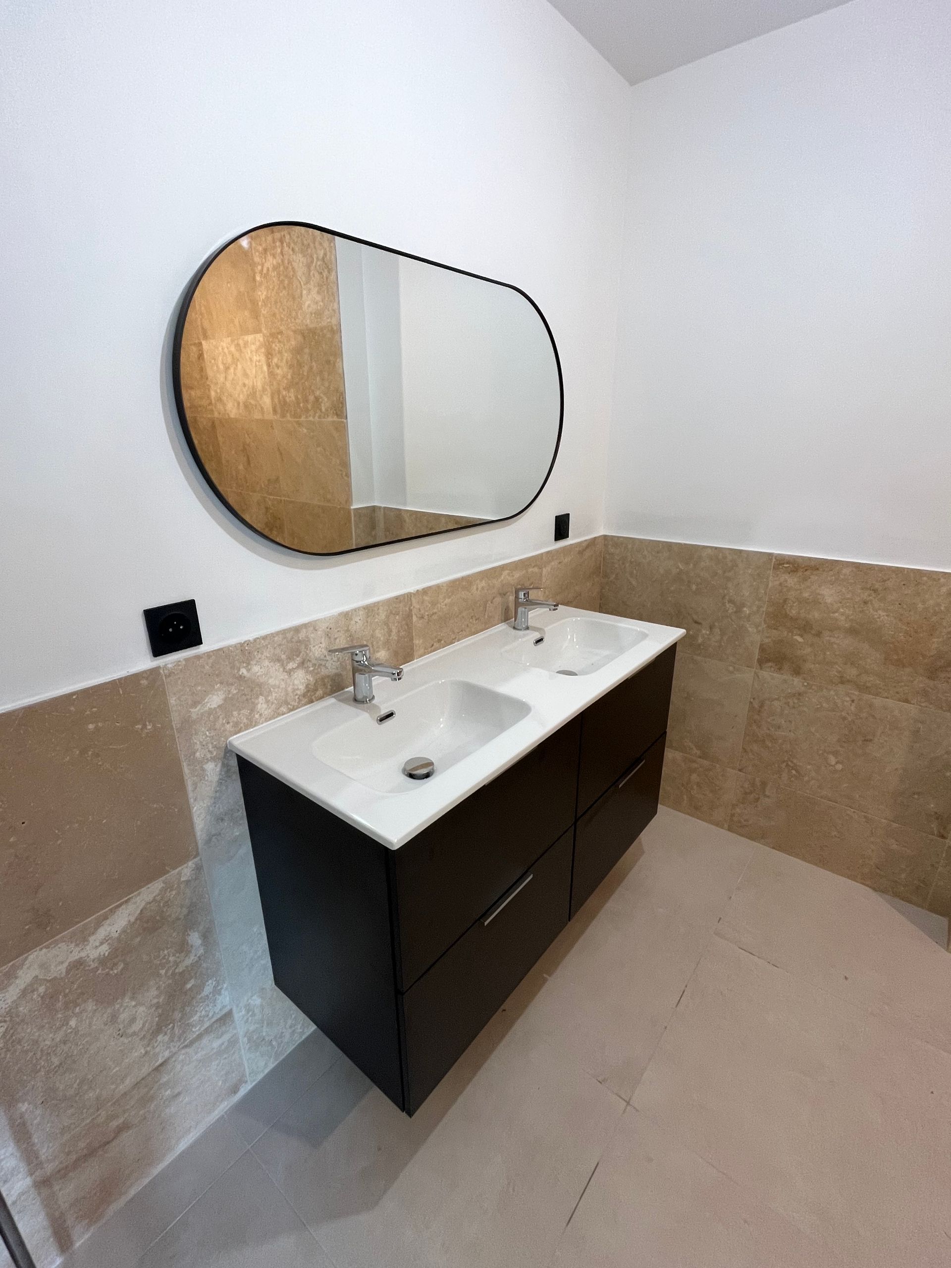 Doubles vasques avec un meuble noir dessous et un miroir horizontal au-dessus