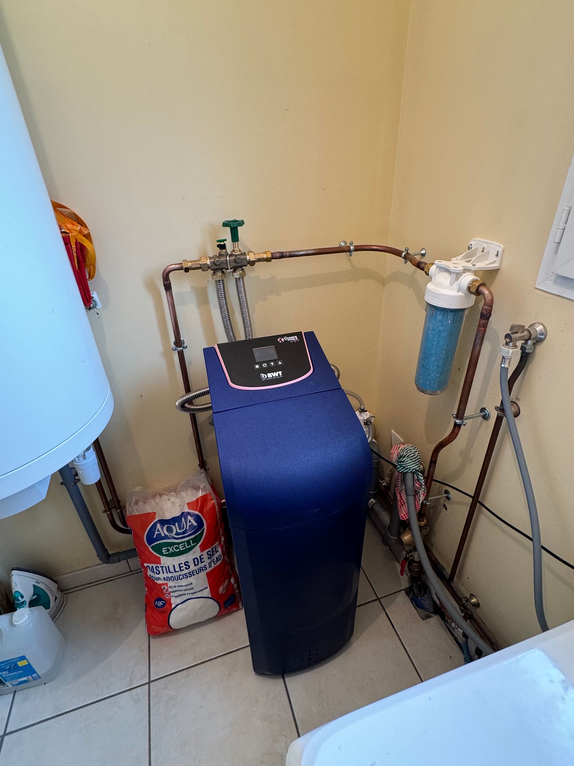 Adoucisseur d'eau avec un sac de pastilles à côté d'une chaudière murale