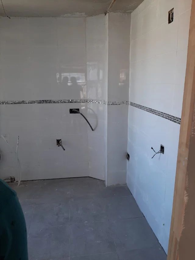 Un baño con azulejos blancos y suelo gris.