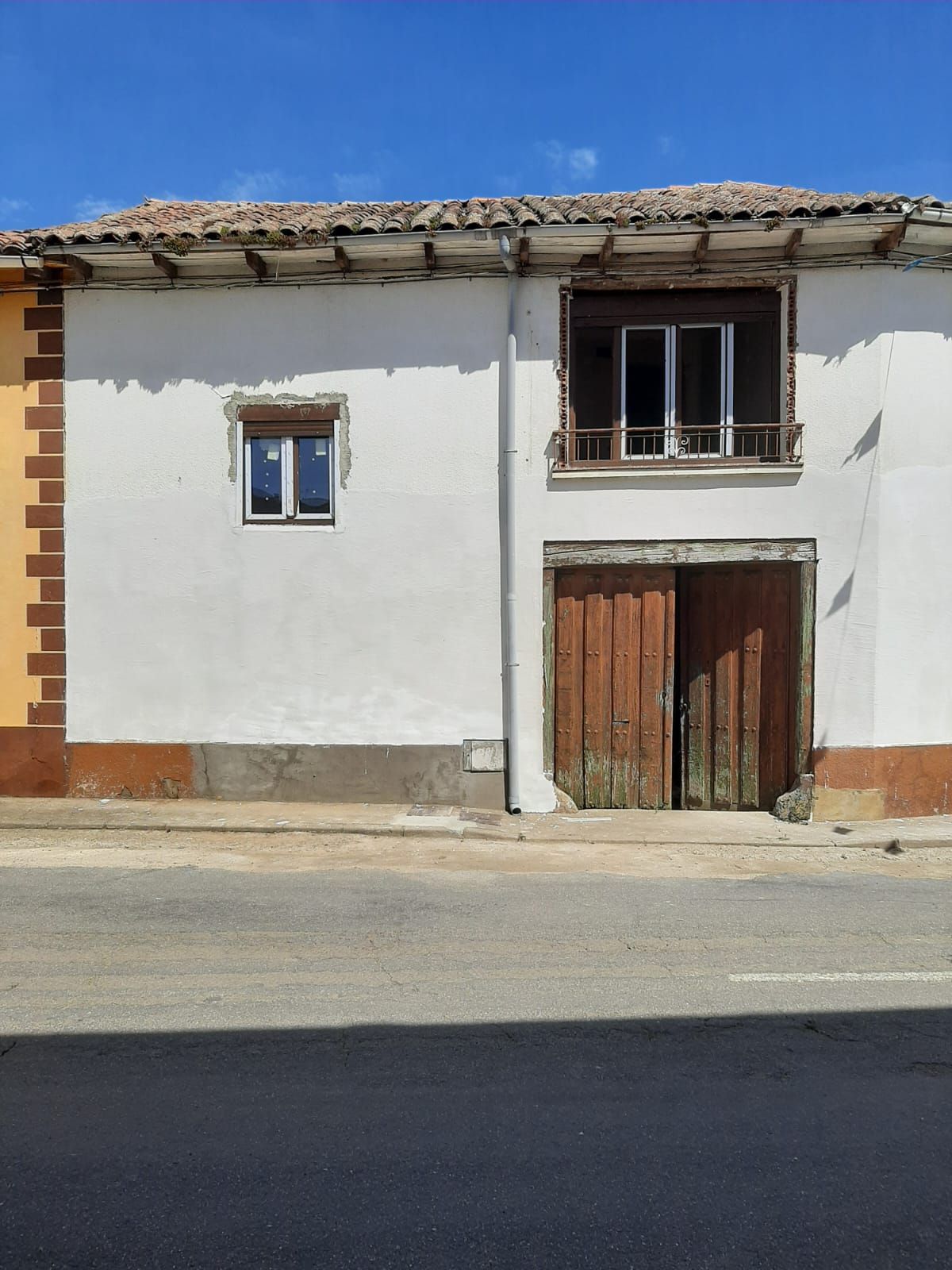 Un edificio blanco con una puerta de madera y un balcón.