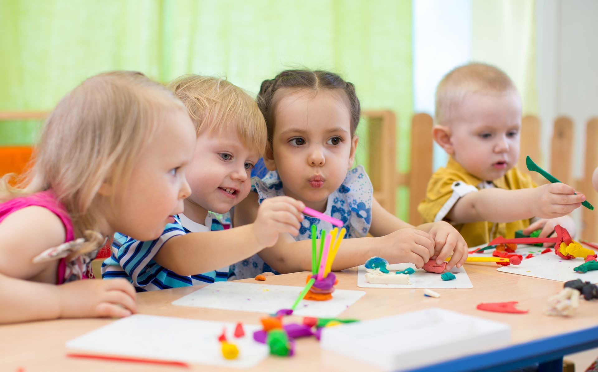 Quatre enfants en train de faire de la pâte à modeler.