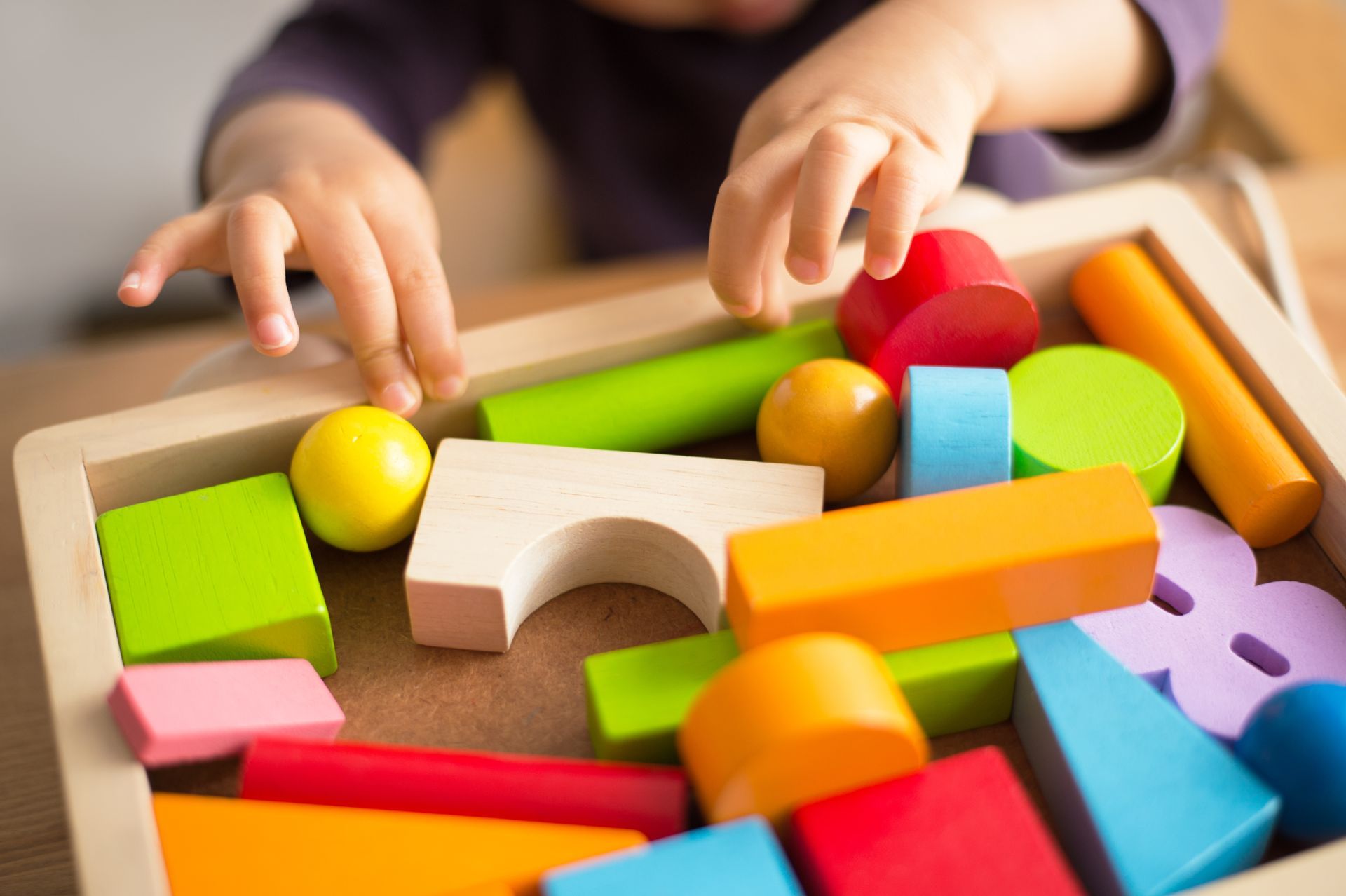 Un enfant jouant avec des jouets en bois colorés.
