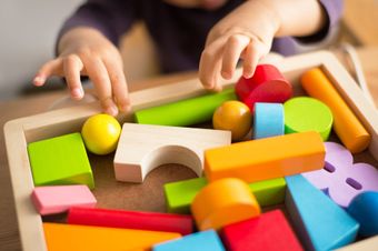 Un enfant touchant des jouets en bois.