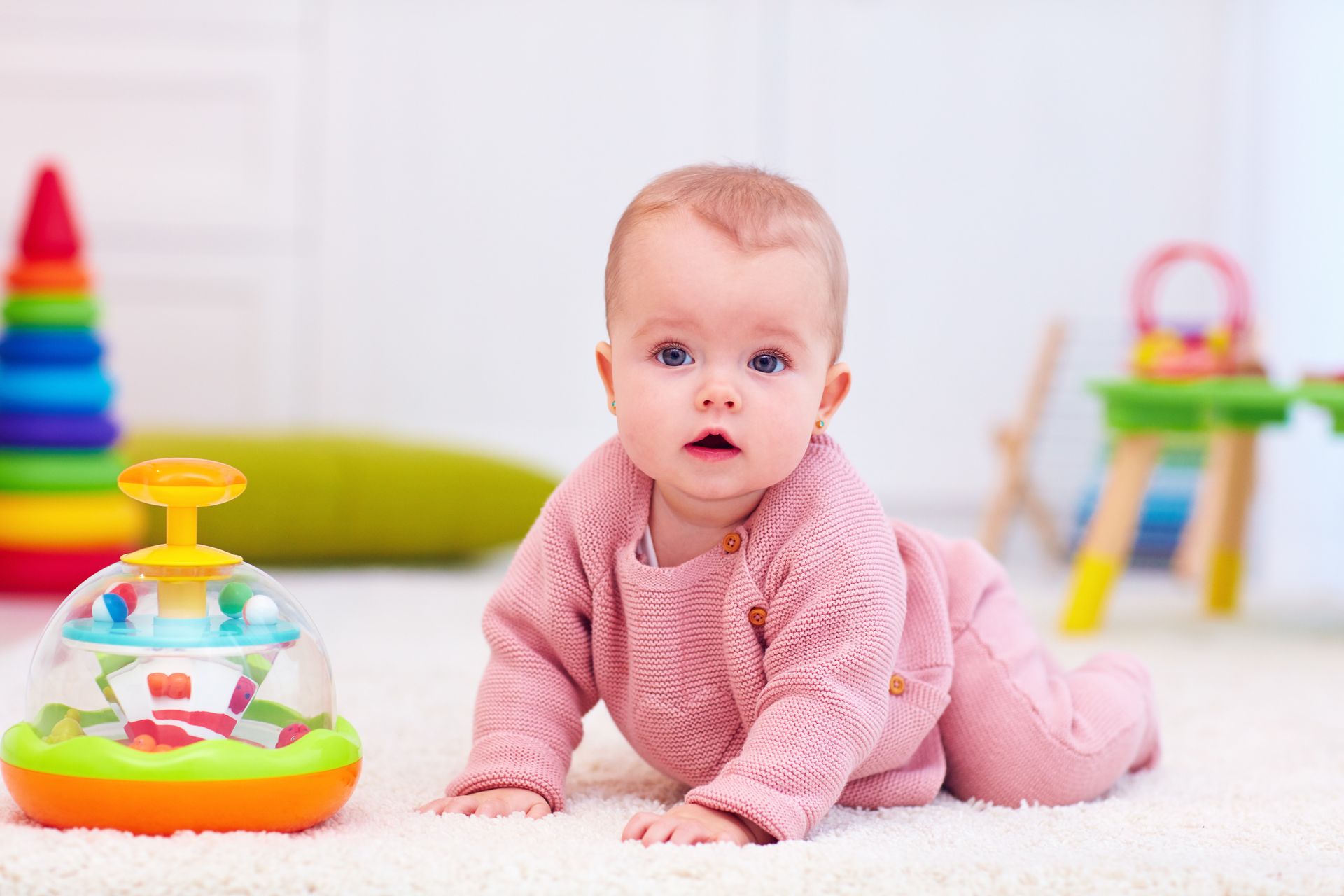 Un bébé à quatre pattes, habillé en rose.