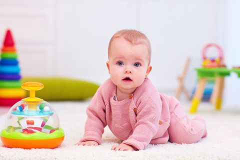 Un bébé à quatre pattes, habillé en rose.