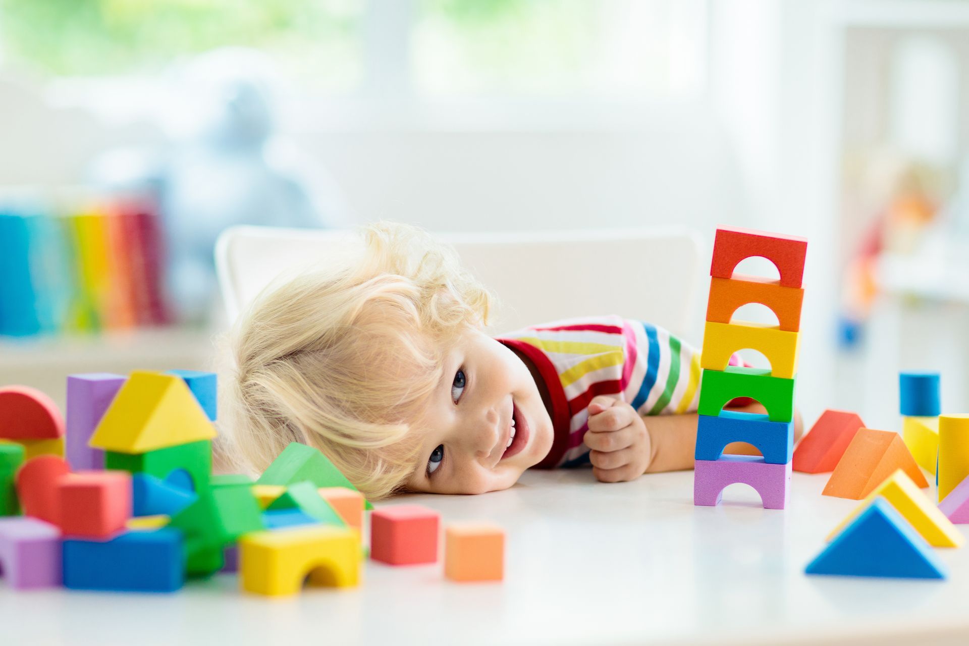 Un enfant couché sur une table avec des jeux.