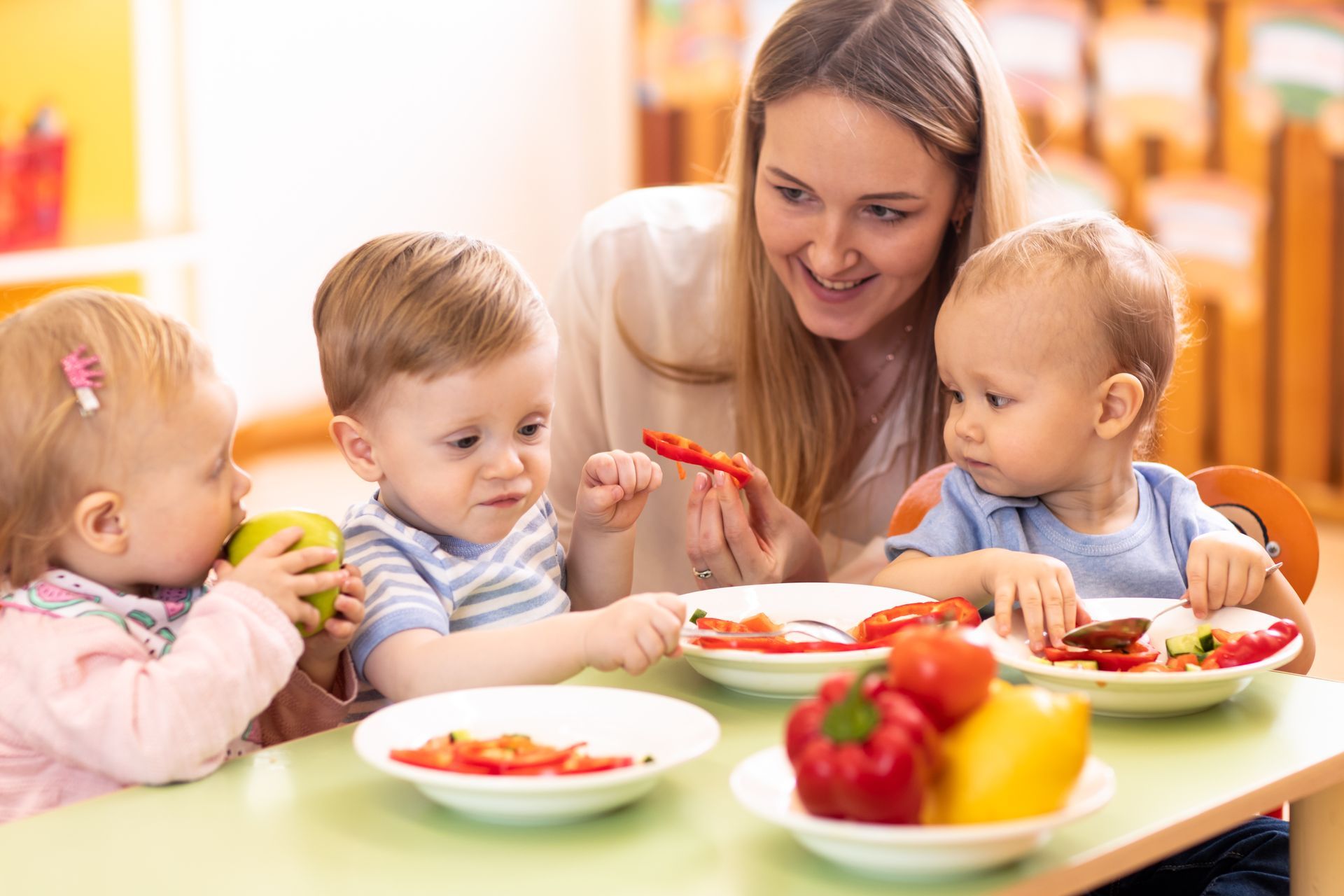 Une femme donnant à manger à trois enfants.