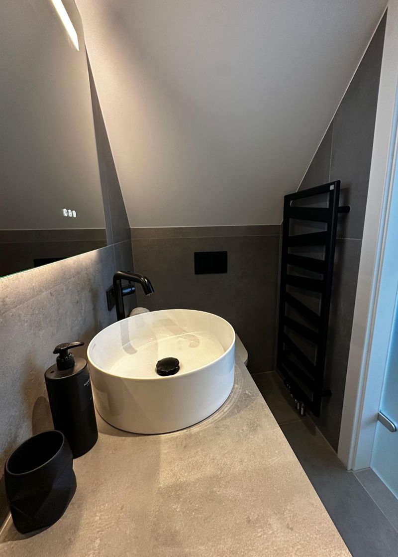 Ein Badezimmer mit Waschbecken, Spiegel und ebenerdiger Dusche.