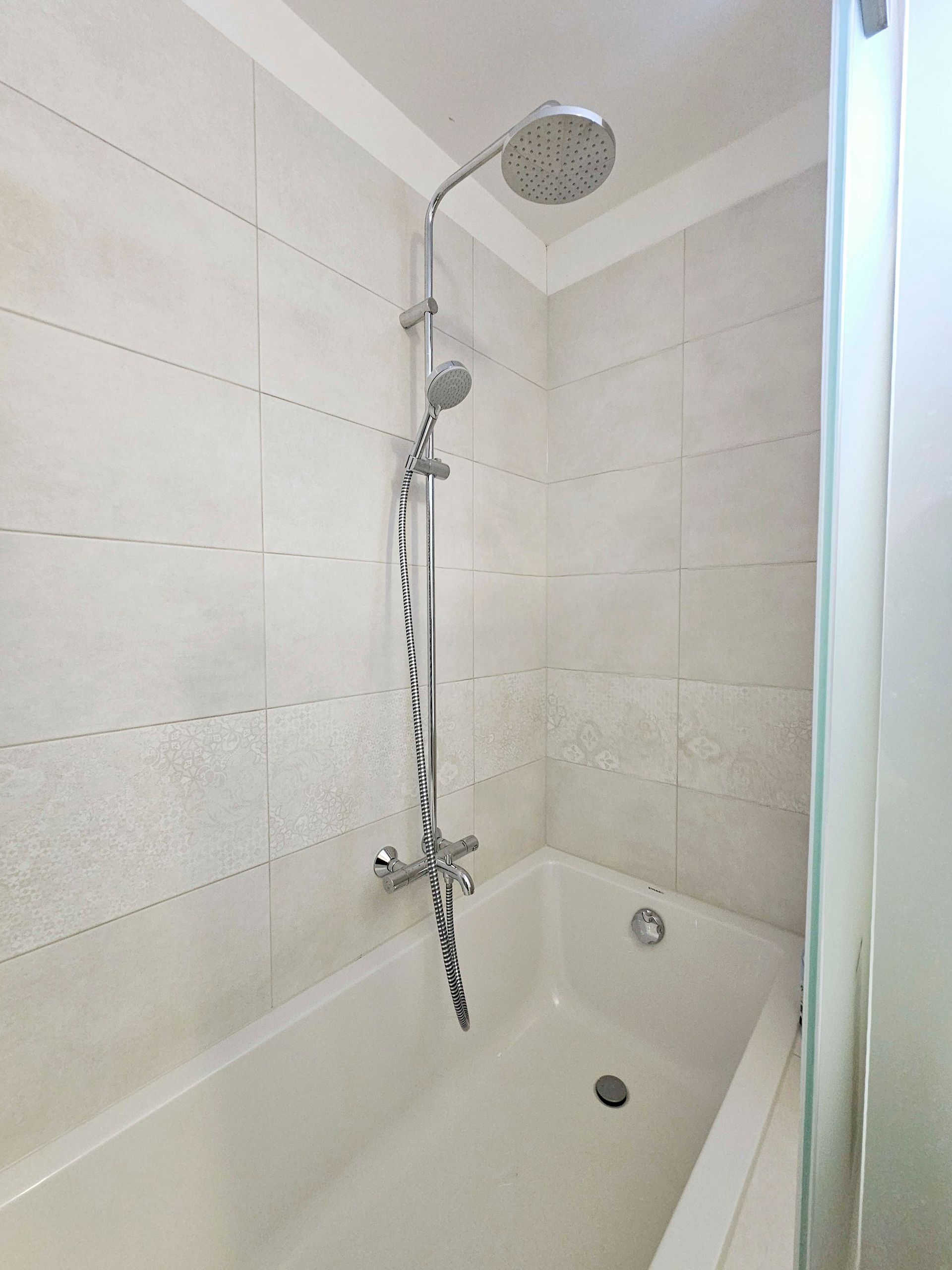 Ein Badezimmer mit Waschbecken, Spiegel und ebenerdiger Dusche.