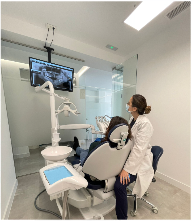 Una mujer con un delantal rosa y azul sonríe en el dentista.