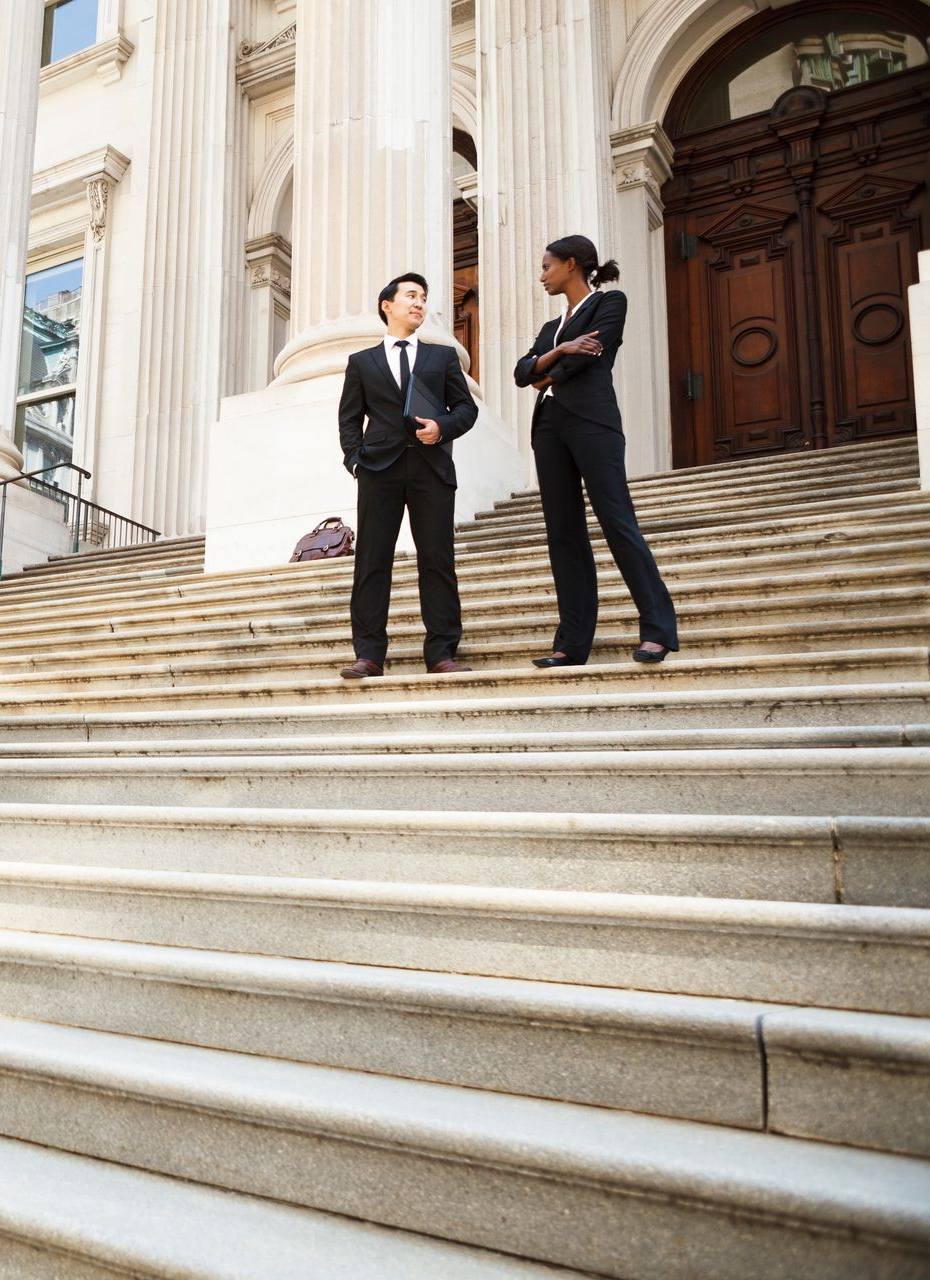Deux avocats discutent sur les marches d'un palais de justice.