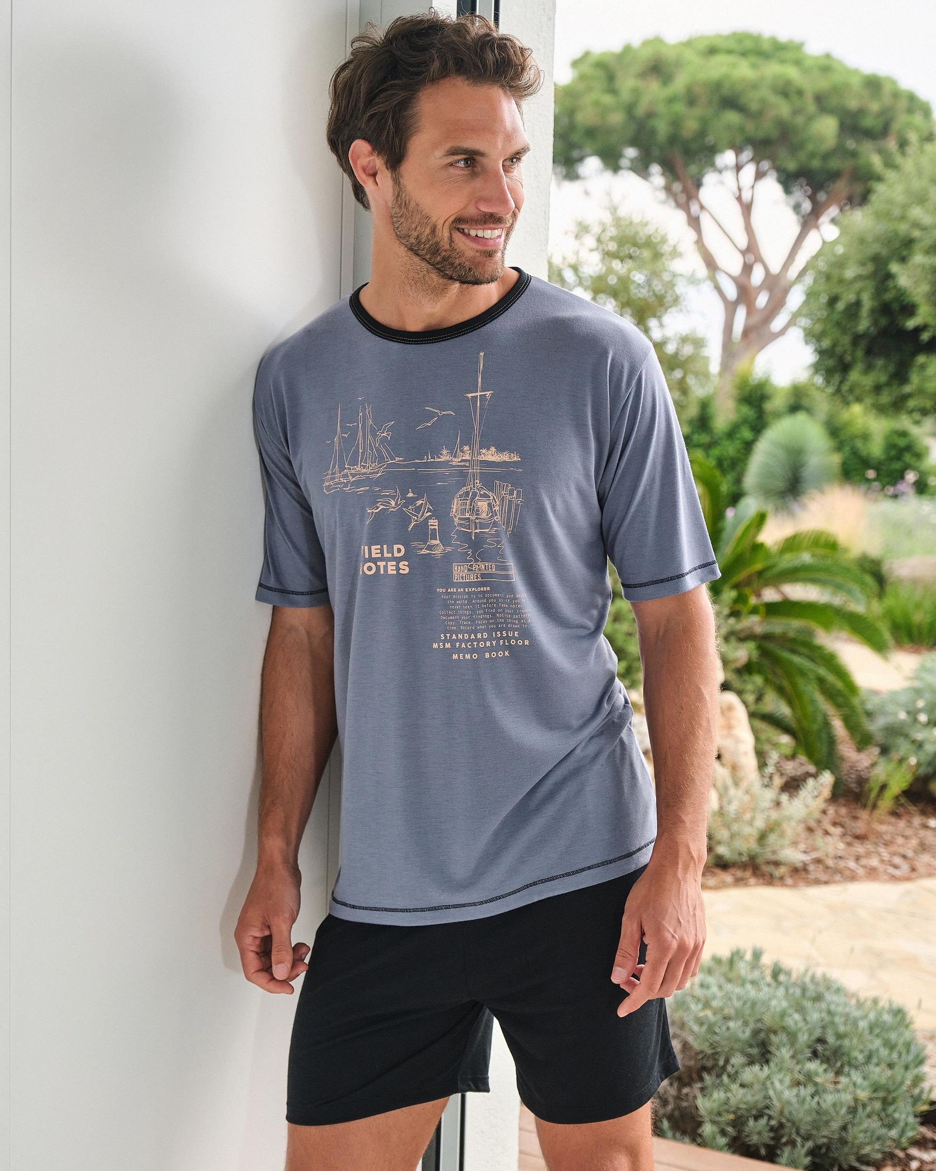 Un hombre que lleva una camiseta y pantalones cortos está apoyado contra una pared.